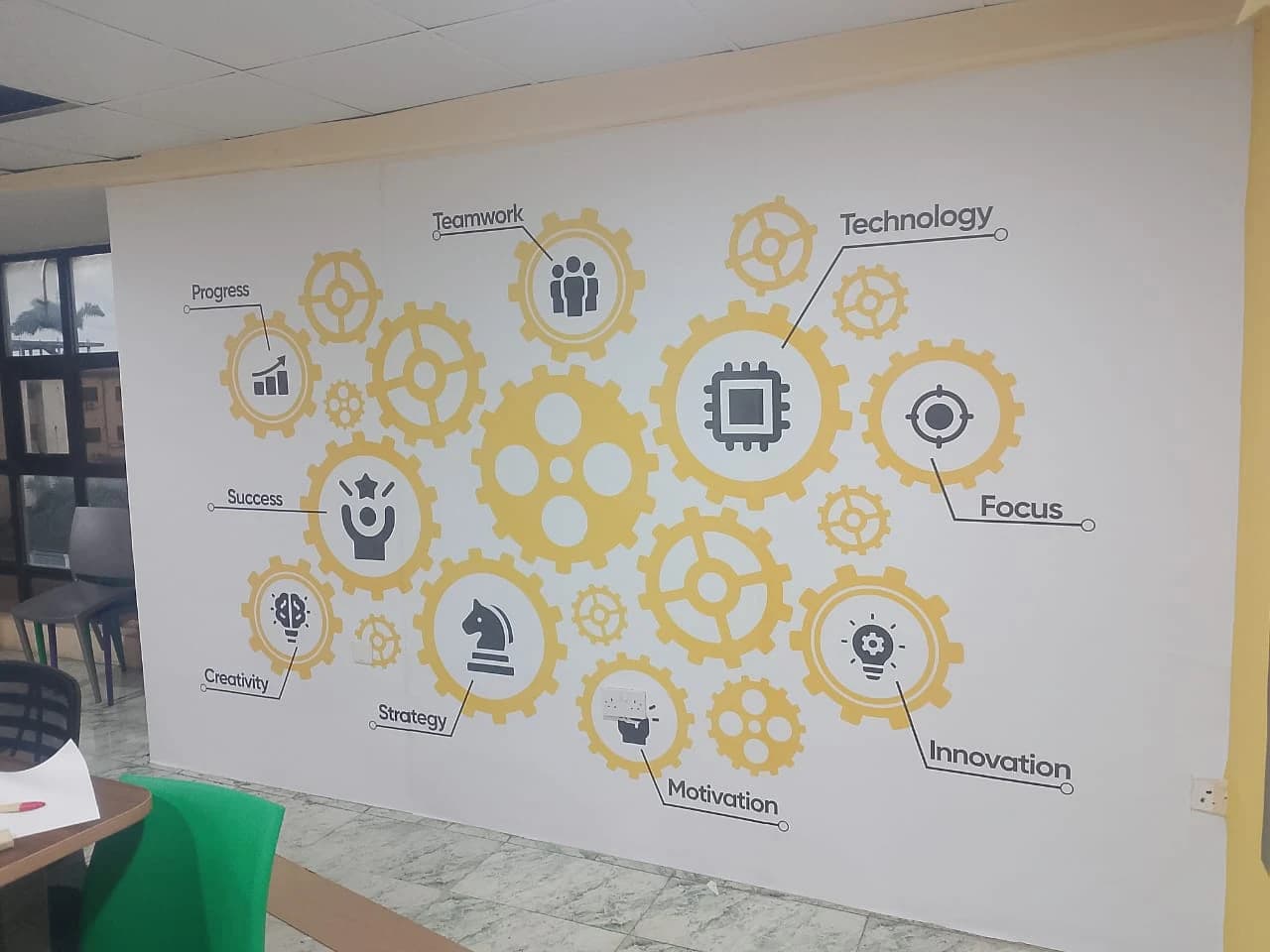 Interlocking yellow and grey corporate strategy gear vinyl graphics installed on an office feature wall.