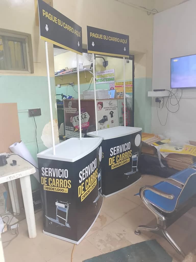 Two black and yellow branded promotional sampling booth counters with overhead header boards in a workshop.