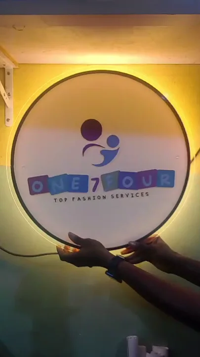 Round illuminated One 7 Four acrylic logo sign displaying a warm perimeter halo glow.
